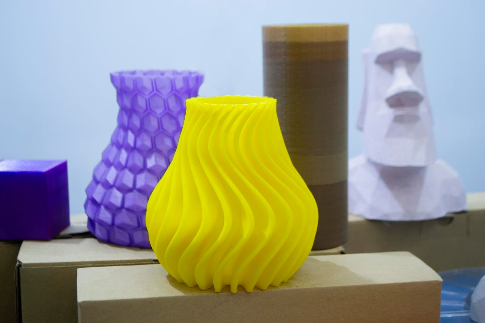 Peças coloridas impressas em 3D expostas sobre caixas de papelão