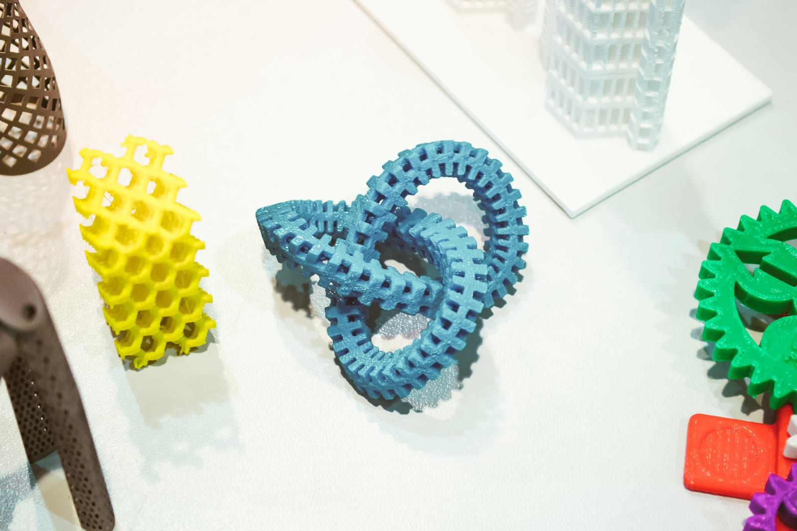 Peças impressas em 3D de várias cores dispostas sobre uma mesa branca